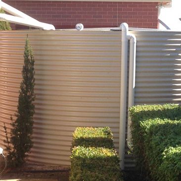 Cream Aquaplate tank with green hedge in foreground