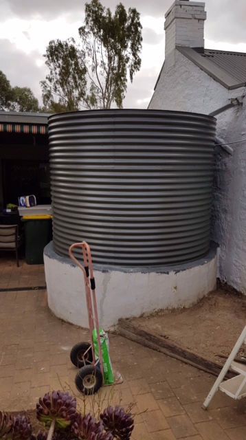 steel grey rainwater tank on white base at cottage in Kapunda SA